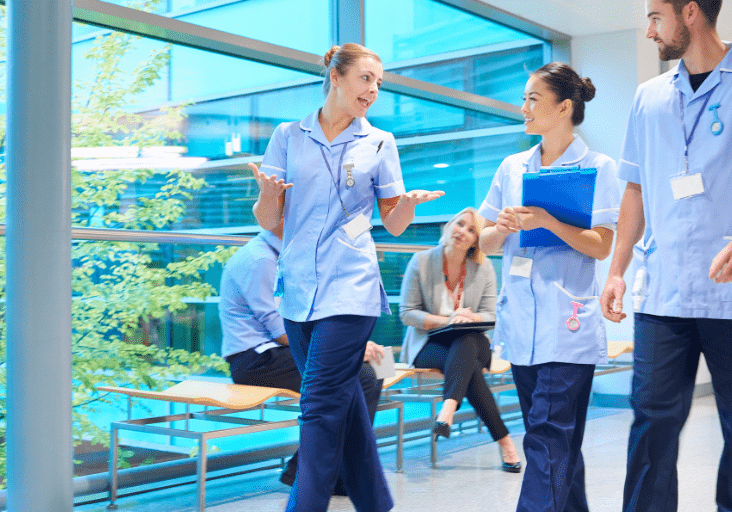 three medical professionals walking and talking in corridor